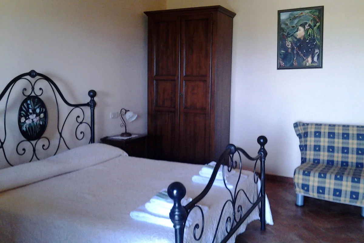 Camera con letto matrimoniale e poltrona a quadretti